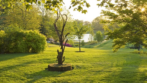 A spring garden, sculpture overlooking a pool.